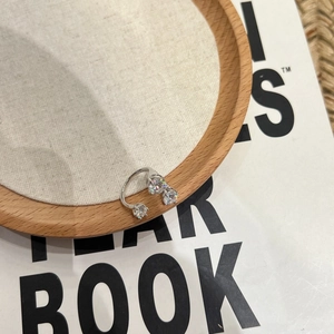 Détail d'une bague ouverte en argent à trois pierres sur lin dans un style épuré