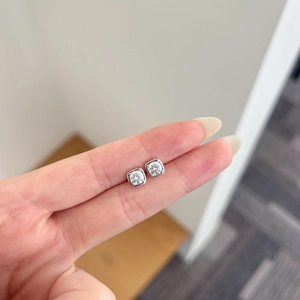 Macro shot of 925 sterling silver square moissanite stud earrings held by hand