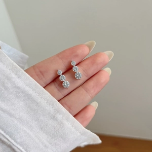 Detail of S925 silver stud earrings with three graduated moissanite stones held by hand