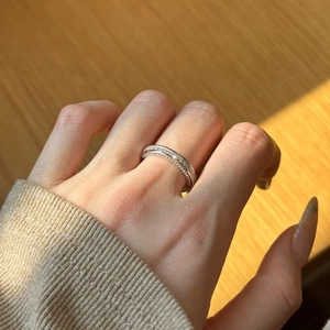 Gros plan d'une bague en argent sertie de deux rangées de strass portée au doigt