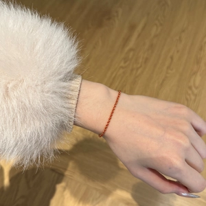 Gros plan d'un bracelet minimaliste en argent S925 à cordon rouge et finition dorée