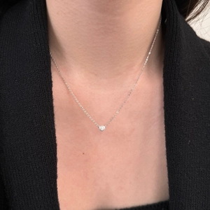 Detail of silver S925 necklace with a round bezel-set solitaire diamond on neck
