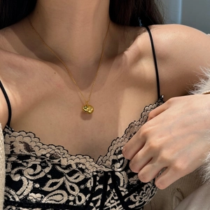 Close-up of elegant gold gourd pendant necklace on female model with lace dress