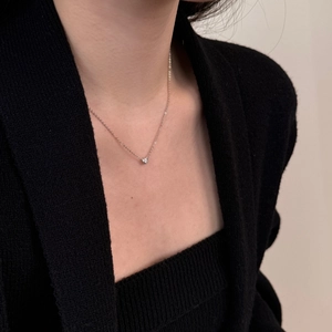 Close-up of a minimalist S925 sterling silver solitaire moissanite necklace on a model