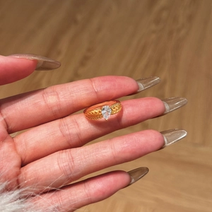 Détail d'une bague dorée texturée épi de blé avec une pierre précieuse en goutte