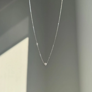 Detail view of a minimalist S925 silver necklace featuring a bezel-set moissanite pendant