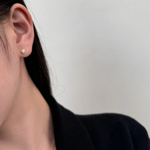 Close-up of minimalist gold-plated silver stud earrings with round solitaire moissanite