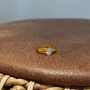 Détail d'une bague épis de blé dorée avec zircon poire sur une surface en cuir sombre