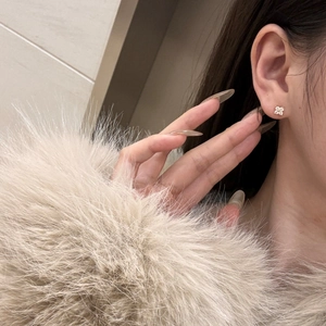 Close-up of sparkling four-leaf clover stud earring in gold finish worn on earlobe