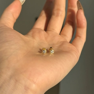 S925 sterling silver gold plated moissanite stud earrings held in a hand for size