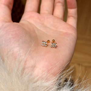 Macro shot of gold floral studs with clear zircon petals held in hand for scale