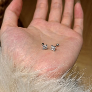 Macro shot of silver four-petal flower stud earrings with zircons and screw ball backs
