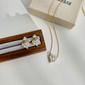Detailed close-up of S925 silver heart necklace and earrings set with gold finish