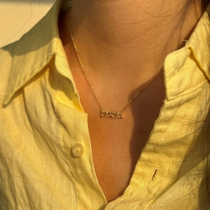 Primer plano de un collar de plata S925 dorado con un colgante mama adornado con diamantes