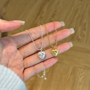 Detailed close-up of heart locket pendants in gold and silver finish with beaded chains