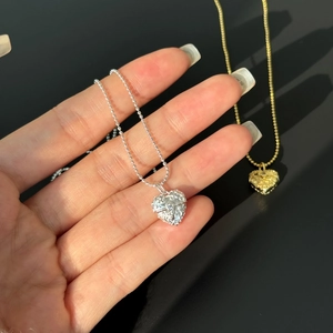 Detailed view of silver and gold heart pendants with intricate vintage scroll engravings