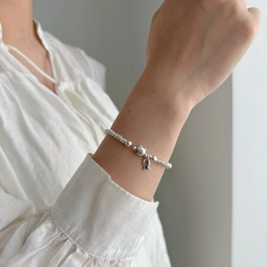 Close-up of S925 sterling silver kitten bracelet with engraved smile fish charm