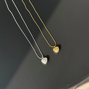 Detailed macro view of vintage gold and silver heart-shaped relief pendants on bead chains