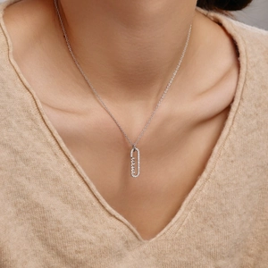 Détail macro du collier pendentif MAMA en argent S925 sur le cou d'une femme pour maman