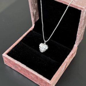 Detailed view of vintage S925 silver heart pendant with floral relief in pink velvet box