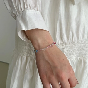 Detail of colorful beaded bracelet with crystal drops on a model wearing white dress