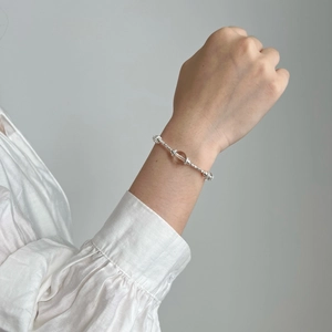 Détail du bracelet en argent S925 avec perle de cristal rose au poignet d'une femme