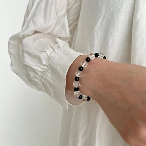 Close-up of minimalist black onyx and clear crystal beaded bracelet on a woman's wrist