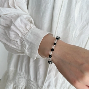 Minimalist black agate and clear crystal beaded bracelet on a woman wearing white