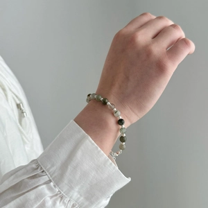 Detailed macro view of S925 silver bracelet with natural green crystal and pearls