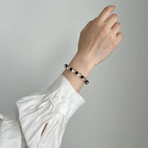 Detailed shot of black onyx and white crystal beaded bracelet on model's wrist