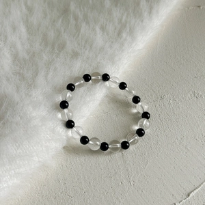 Detailed close-up of a minimalist black agate and clear quartz beaded bracelet on soft fur
