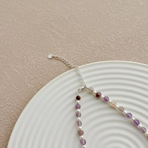 Gros plan sur le poinçon S925 d'un collier en quartz fantôme violet et perles délicates