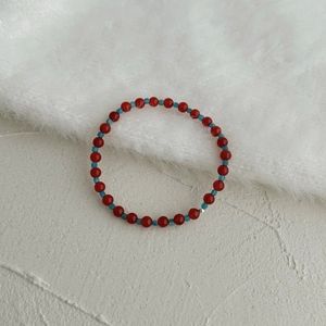 Detailed shot of red agate and blue apatite beaded bracelet on white textured background