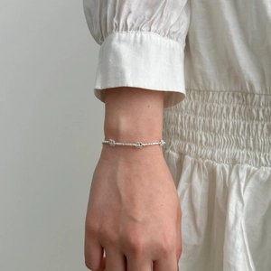 Detail of silver butterfly bracelet with irregular beads on female wrist