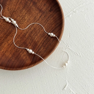 Élégant collier en argent sterling S925 avec perles blanches sur un plateau en bois minimaliste
