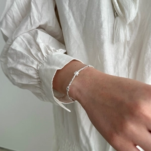 Minimalist S925 sterling silver butterfly bracelet with floral charms on a female wrist
