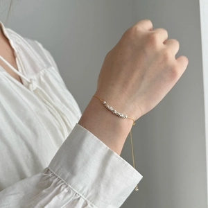 Detail of minimalist two-tone silver and gold chain bracelet on a model wrist