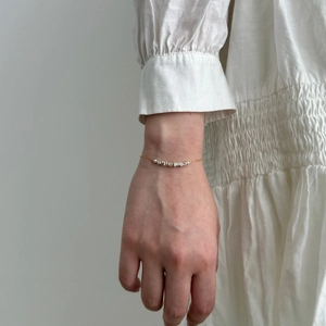 Detail of minimalist two-tone silver and gold chain bracelet on a female wrist