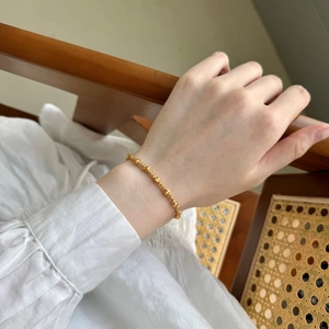 Détail d'un bracelet en argent S925 avec des perles dorées polies et mates sur le poignet