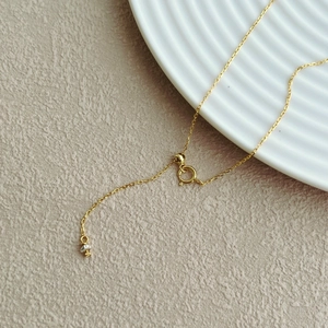 Detail of gold chain clasp with adjustable slider bead and small sphere charm
