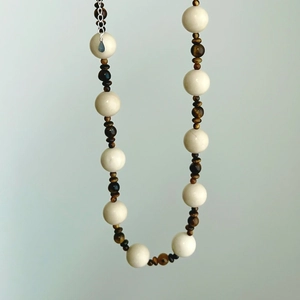 Detail of beaded necklace featuring tiger eye stones and milky white round beads with silver chain