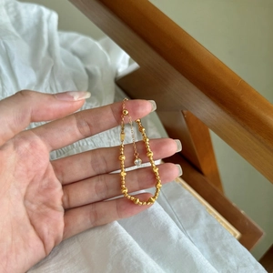 Détail d'un bracelet en perles plaqué or 22k avec breloque œil de chat et cristal