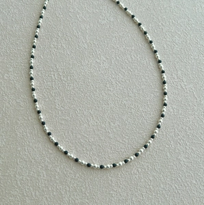 Detail of beaded necklace with alternating silver round beads and black faceted beads