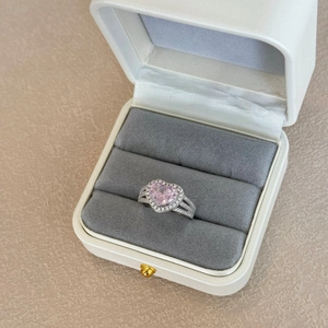 Macro shot of a heart-shaped pink gemstone ring in a velvet lined white jewelry box