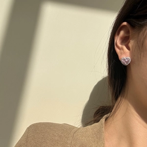 Close-up of pink heart stud earrings with halo setting worn by a female model