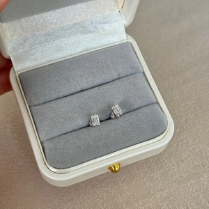 Macro shot of silver stud earrings with emerald-cut crystals in a white jewelry box