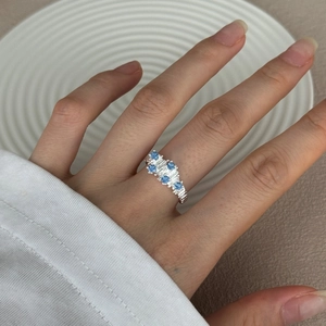 Detail of S925 silver ring with five sky blue zircons and textured band on finger