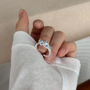 Detail of S925 sterling silver ring with blue zircons on a hand with irregular textures