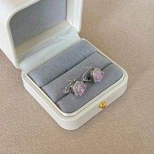 Macro shot of silver heart earrings with pink stones in a white leather jewelry box