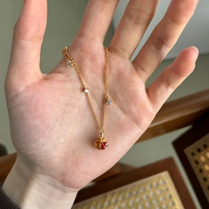 Détail d'un pendentif grenade doré avec gemmes rouges et oranges sur une chaîne fine